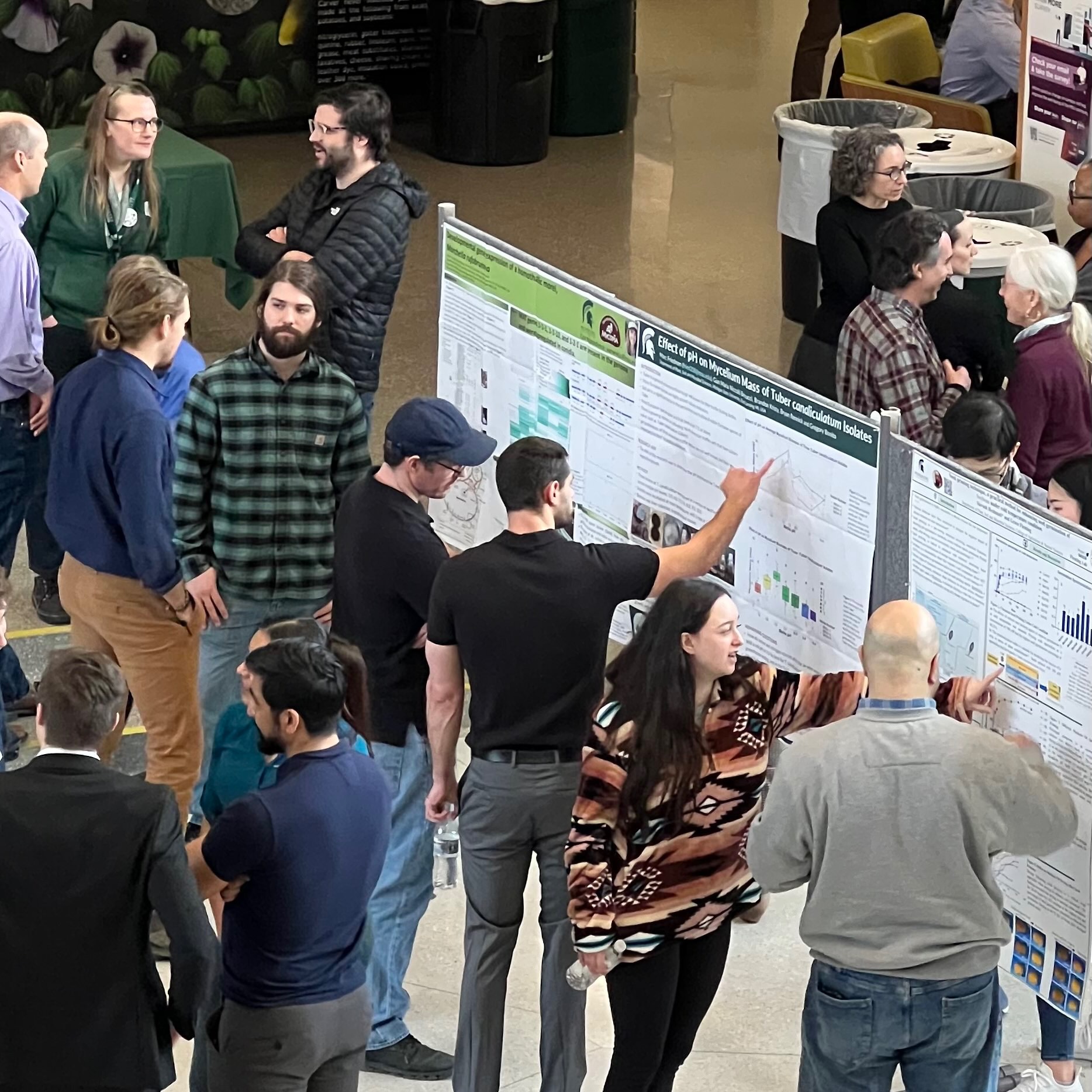 Recruitment weekend attendees talk around research posters. 