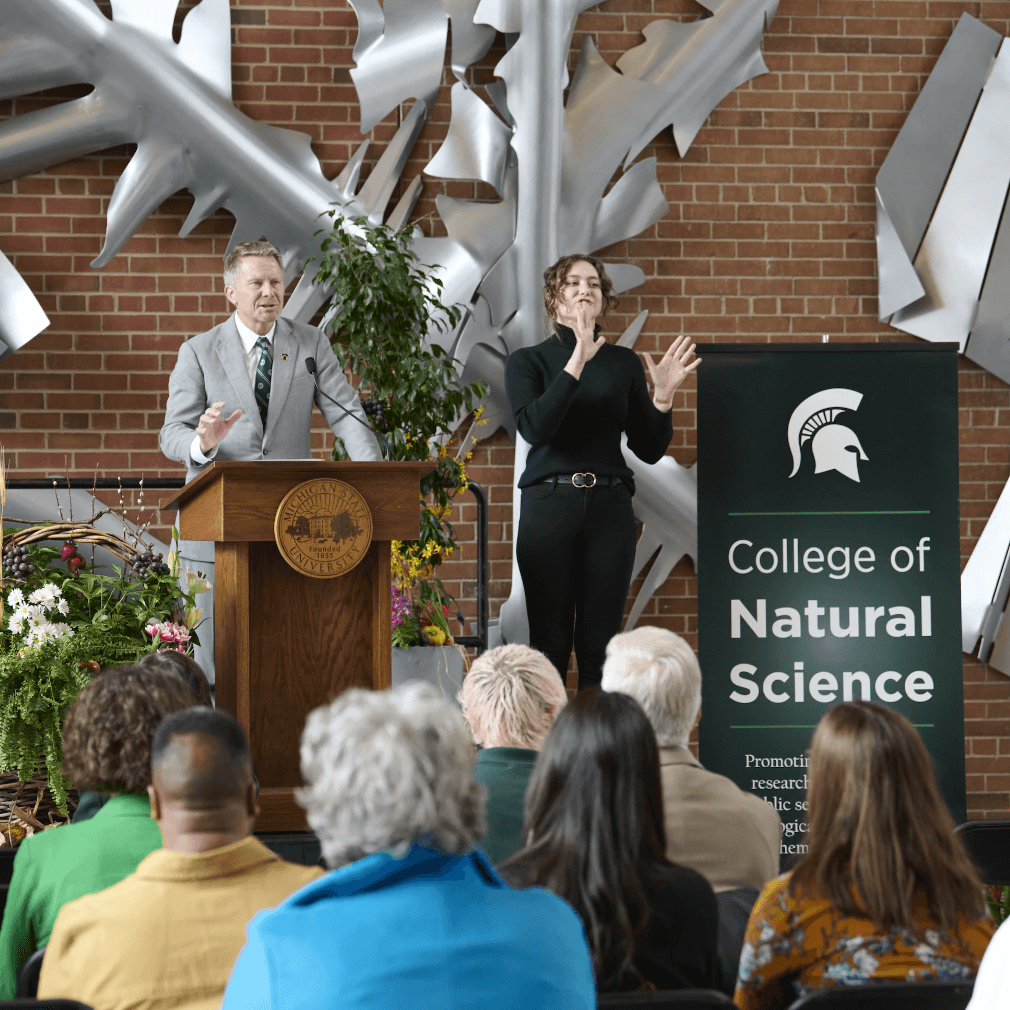 President Guskiewicz and an interpreter address a crowd in the atrium of the Molecular Plant Sciences Building