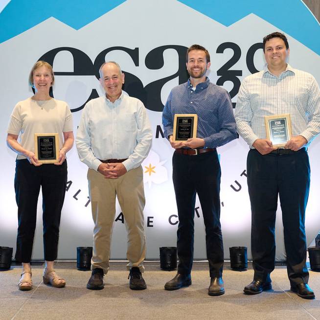 four people holding award plaques